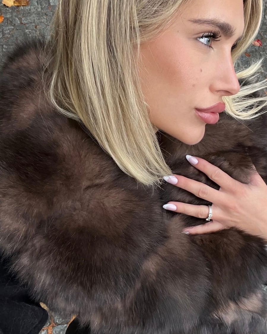 Large col en fausse fourrure brune d’un manteau noir, porté en extérieur